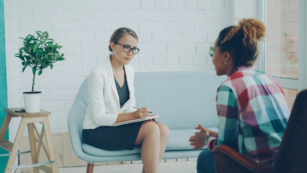 Two people talking calmly in a bright, comfortable counseling room