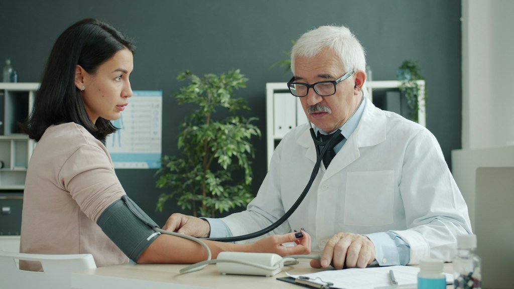 A clinician checking a patient’s blood pressure during an office visit